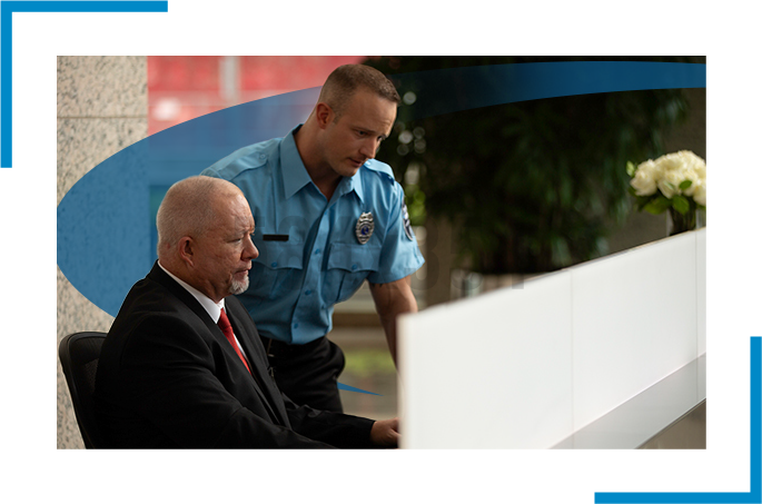 two security guards in the reception looking at a computer